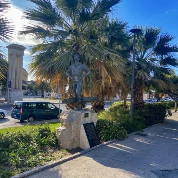 a statue of a man on a rock with palm trees in Malaga