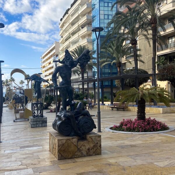 a statue of a man in a courtyard with palm trees and buildings in Marbella
